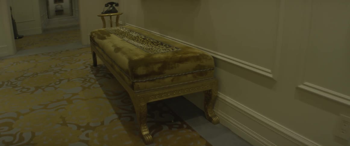 A yellow bench near an antique phone in a hallway