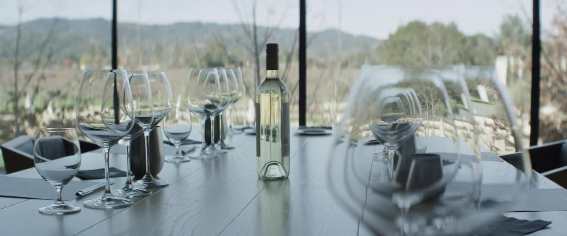 Wine glasses and a bottle sit on a shiny table