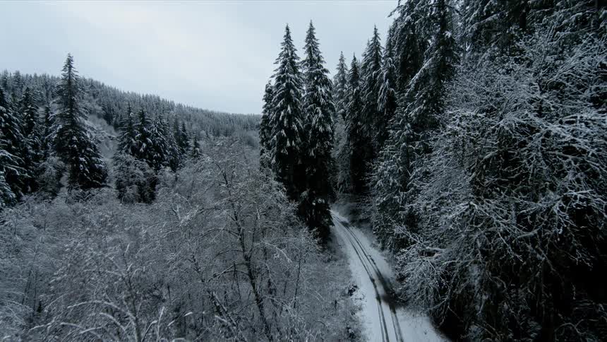 A drone flies along a snow covered dirt road