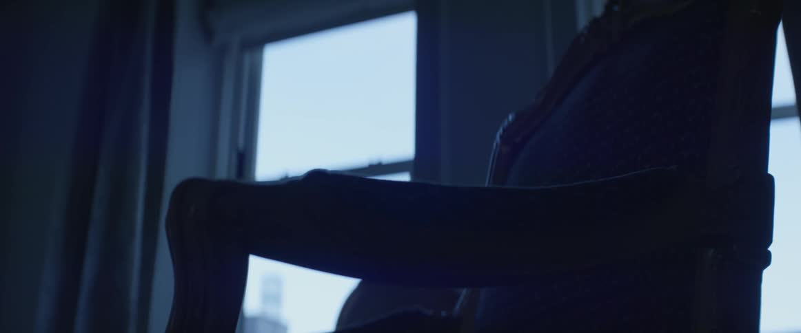A chair sits next to a window in a dark room