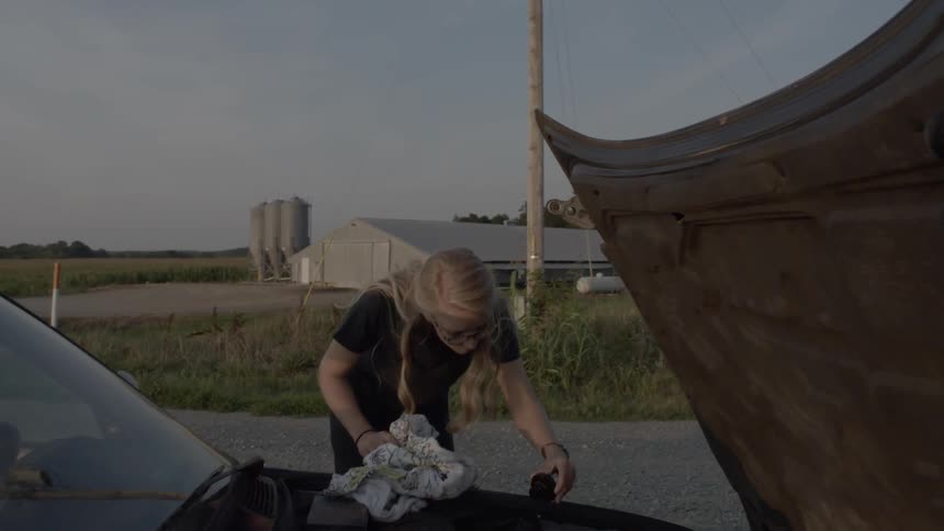 Woman with car trouble removes a cap from the engine