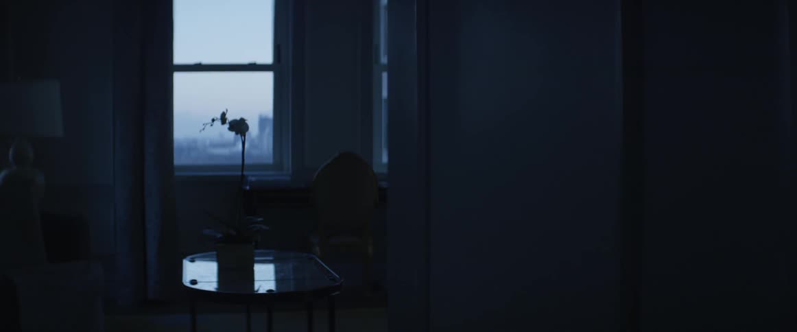 An orchid is sitting in a pot on a table in an empty room