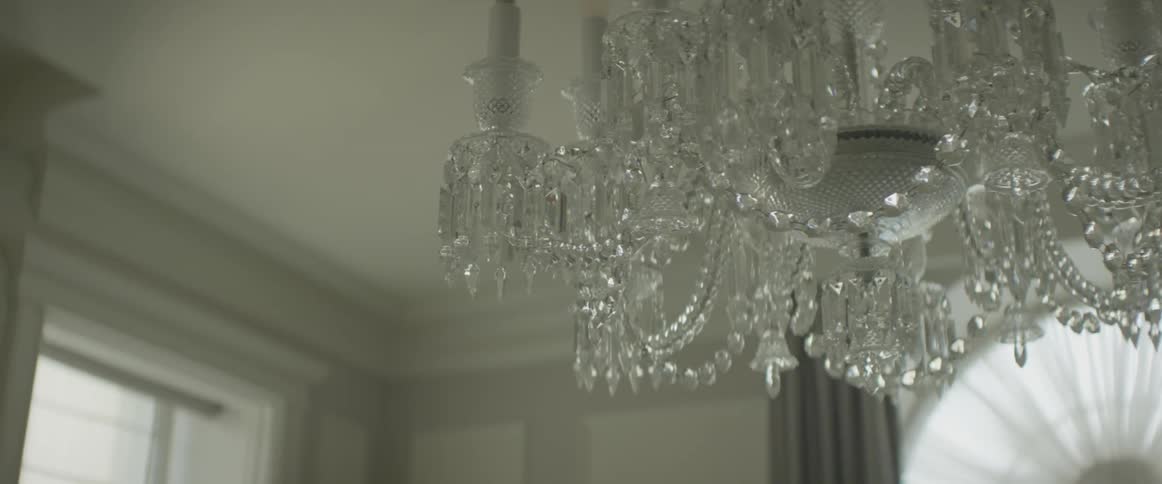 A chandelier hangs from a ceiling in a home during the day
