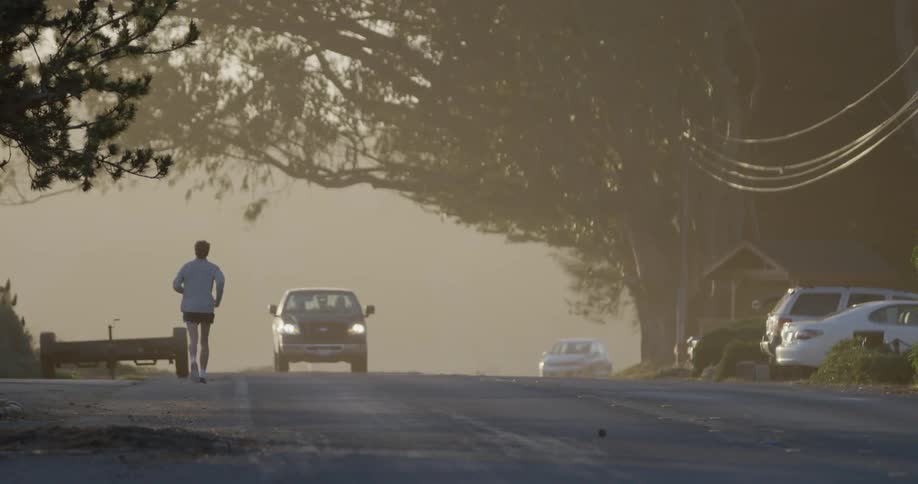 A man jogs on a busy neighborhood street in the early morning