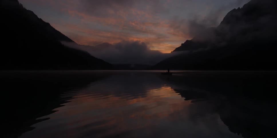 Water gently ripples in a lake near the mountains