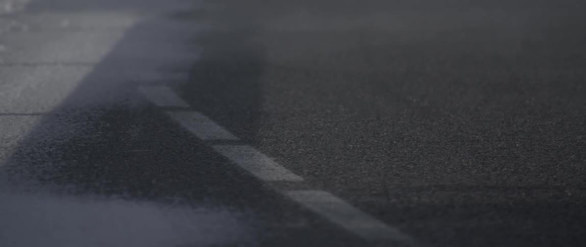 Mist drifts across a road during the day