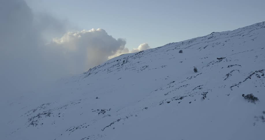 A snow covered mountain is foggy