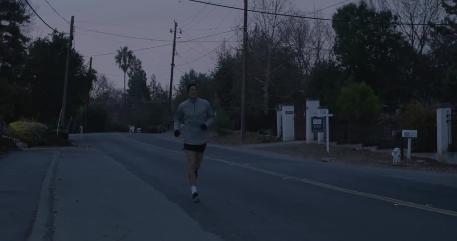 A man running by a sidewalk during sunrise