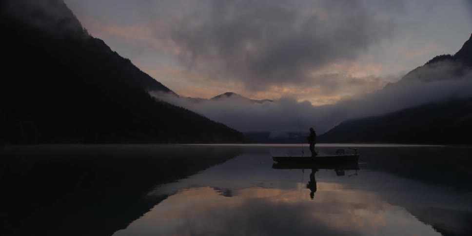Man walks along the edge of a boat that is sitting in a lake