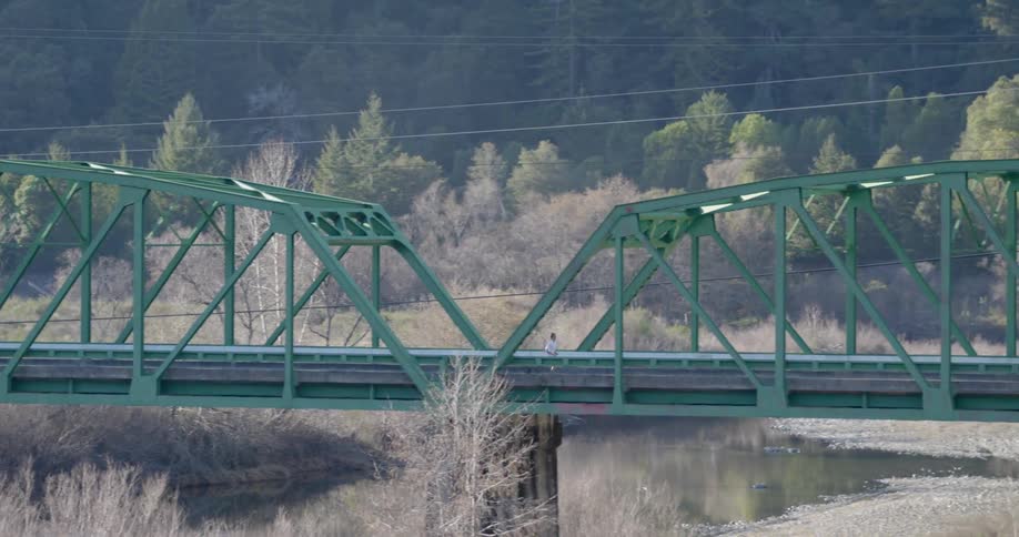A man jogs across a rural bridge