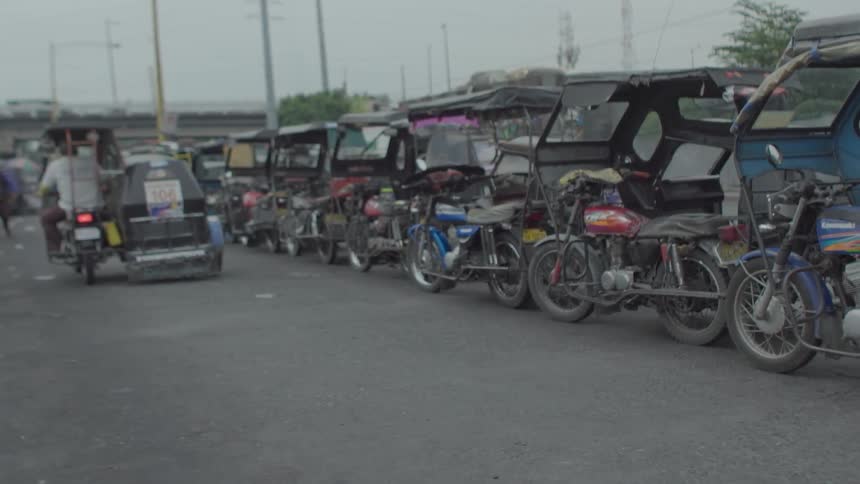 A large group of covered motorcycles are filmed on a road