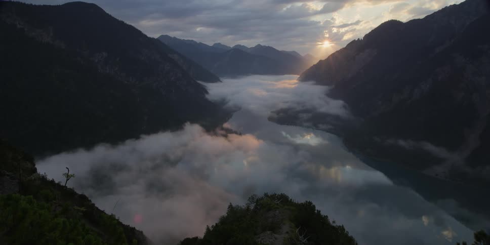 Clouds hover in a mountain valley at sunset
