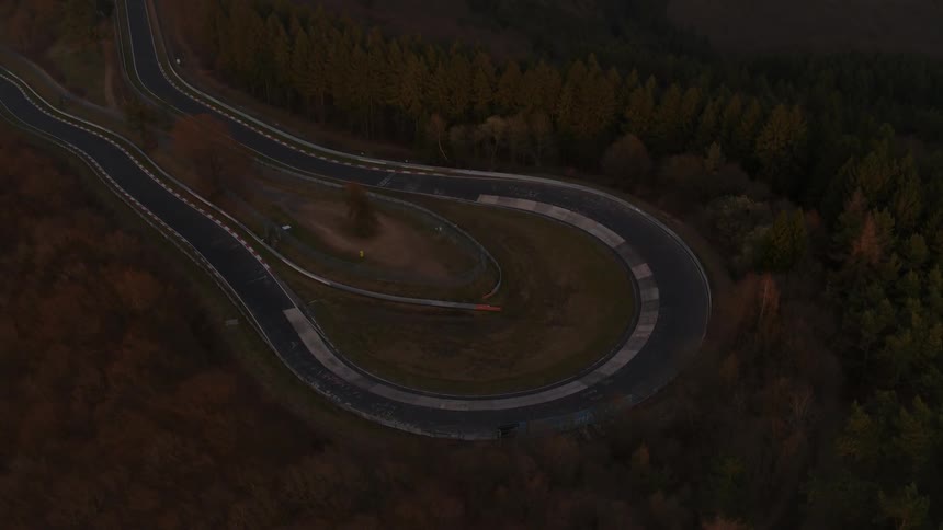 A road in the middle of the woods is filmed from a drone