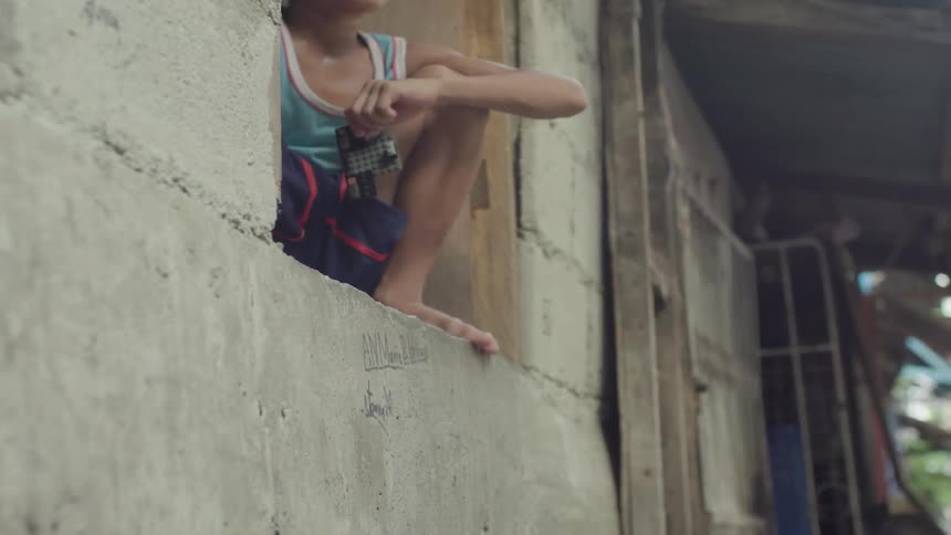 A boy is sitting squatting in a window of a home