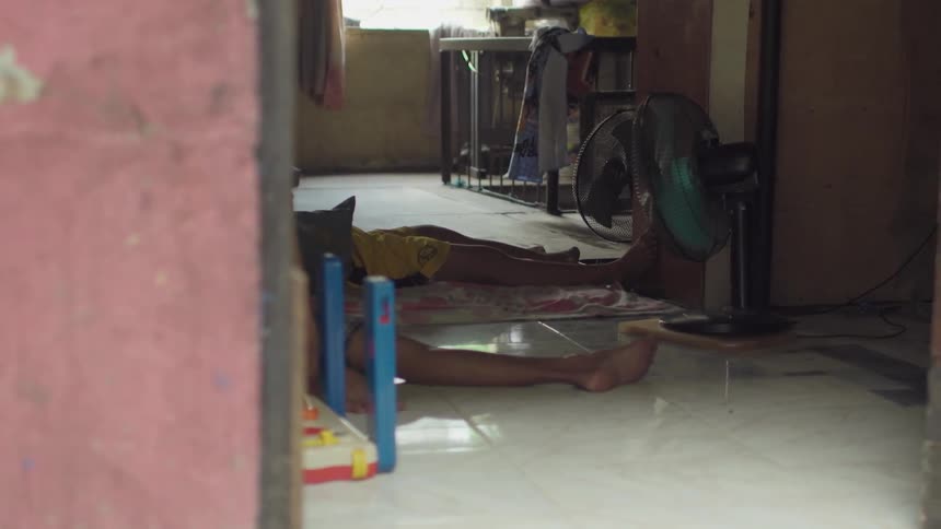People lay on a tile floor near some fans