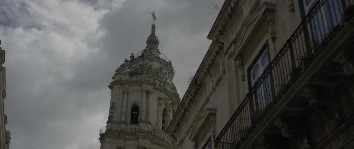 Ornate cement buildings sit under a cloudy sky