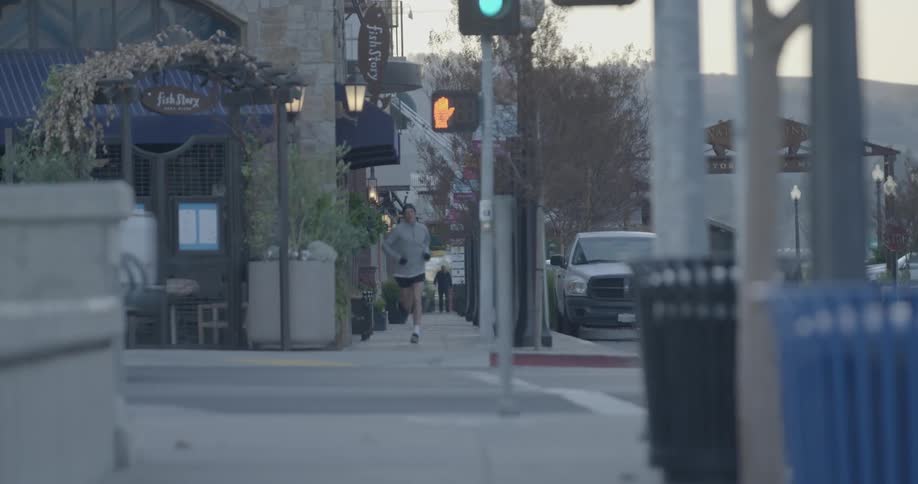 A man jogs down a sidewalk in a city