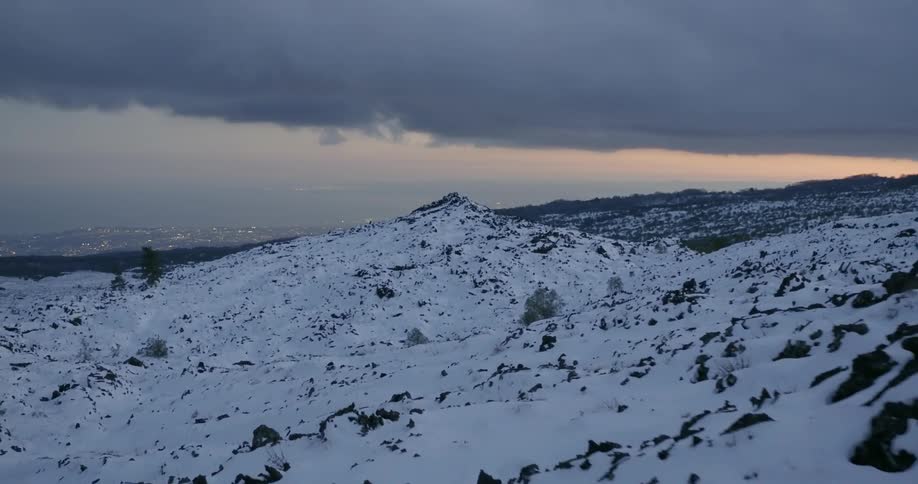 Clouds are hovering over snow-covered hills at dusk
