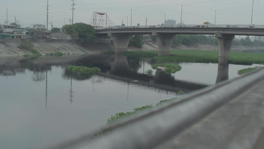 Cars pass on a bridge over a city river