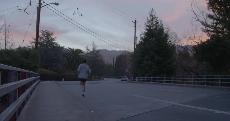 Man runs down a road on a cloudy day