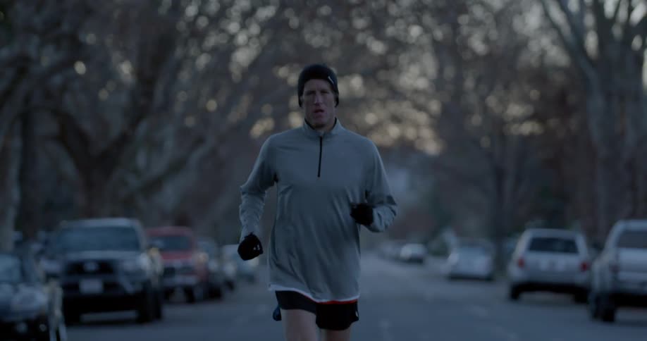 A man jogs down a street at dusk