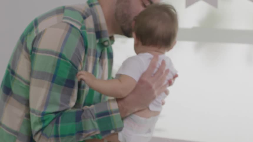 A man is lifting a baby up from a changing table
