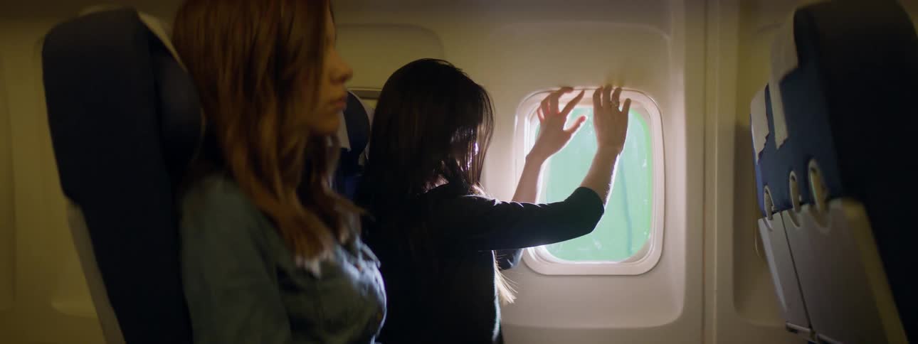 A woman shuts the shade on an airplane window