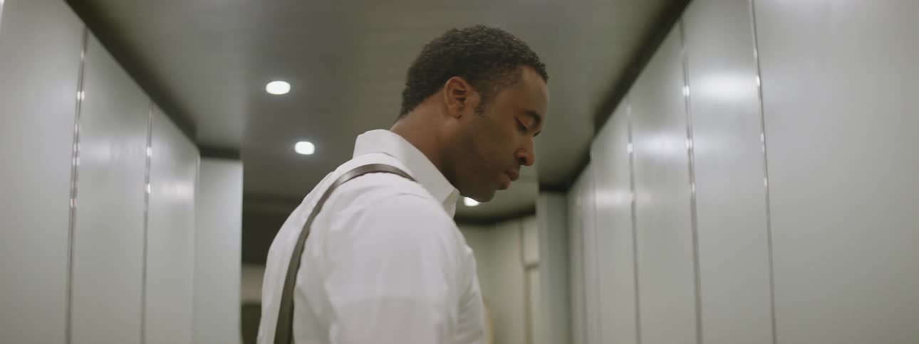 A man in a white dress shirt and satchel is walking through a building