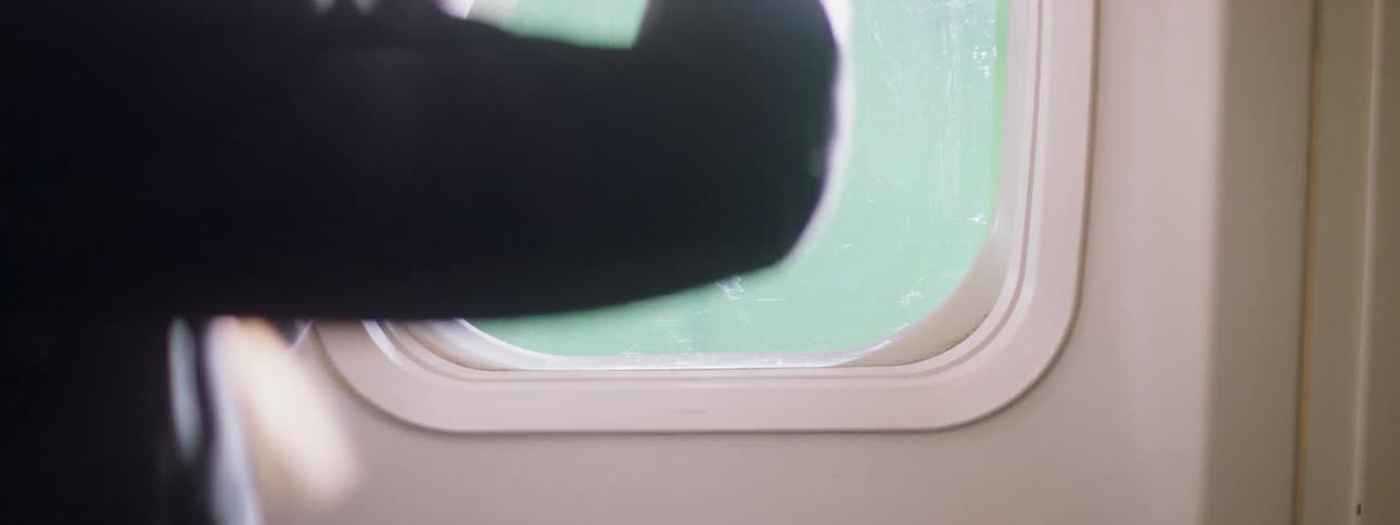 Someone is opening an airplane window