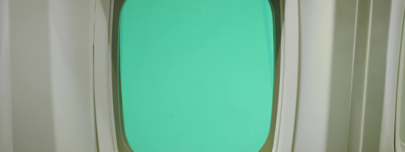 The sky outside a plane window is green