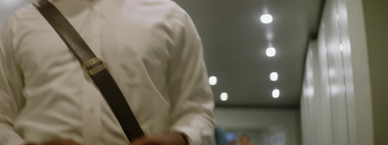 A black man walks nervously down a corridor into a plane