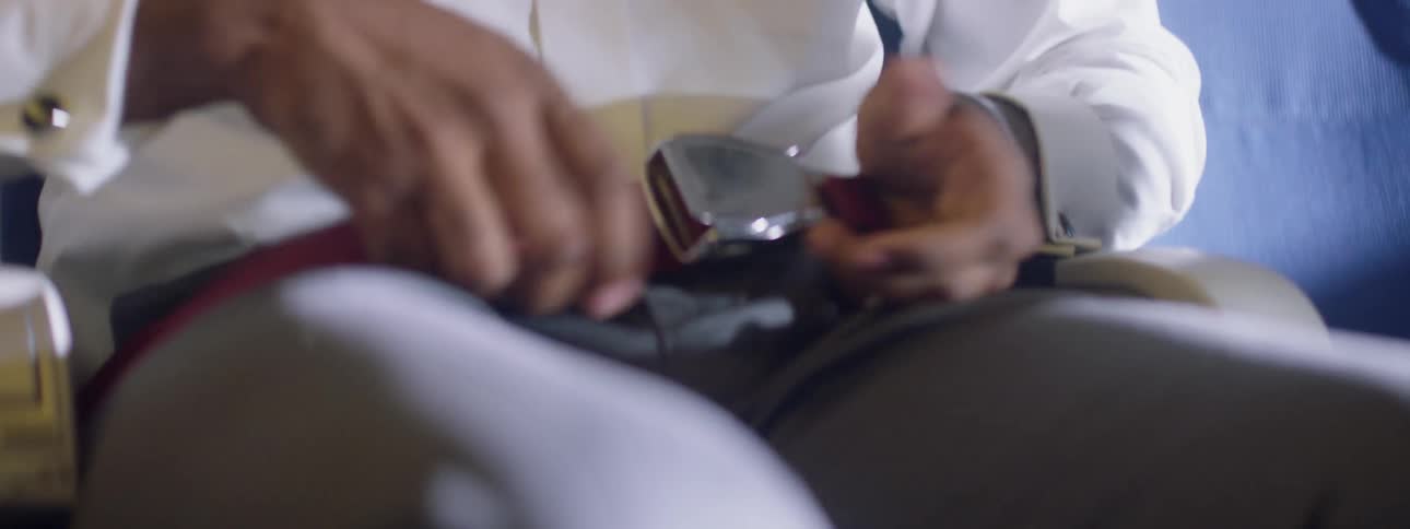 A man sits anxiously and fastens his airplane belt