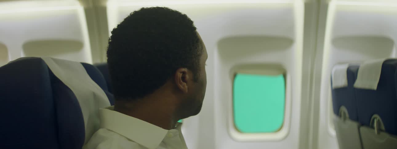 Man looks at window while riding in an airplane