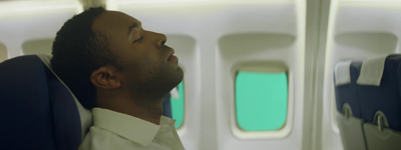 Man on an airplane leans his head back