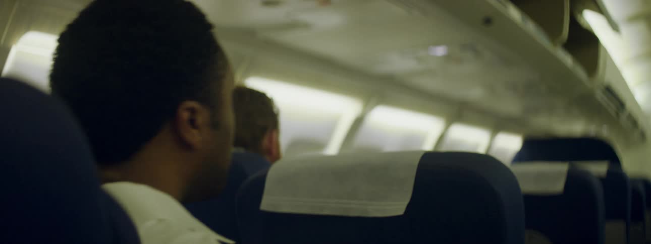 A male passenger fidgets in an airplane seat