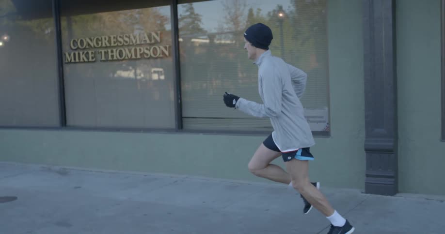 A man runs on a sidewalk in the day time