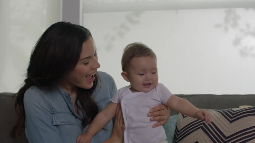 Smiling woman and baby sitting on a couch