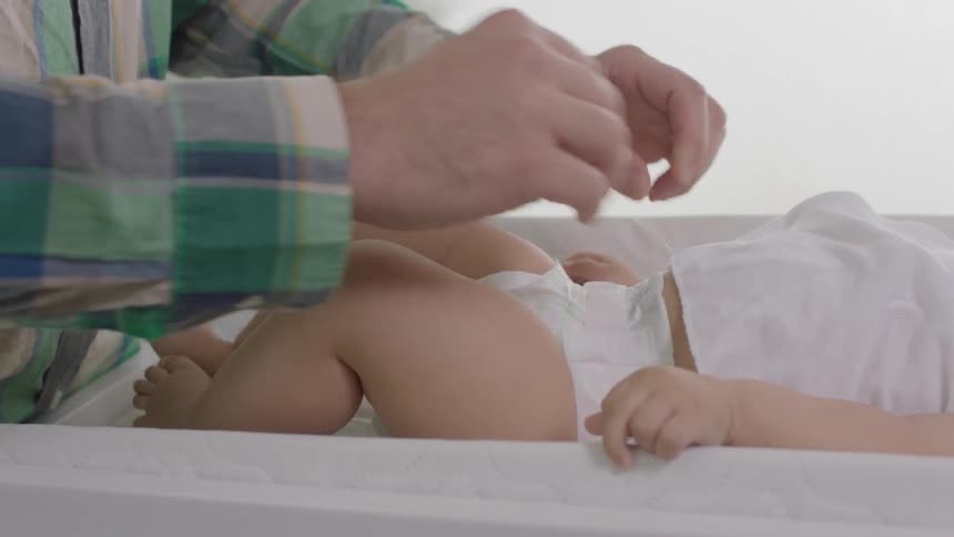 A man is finishing changing a baby's diaper
