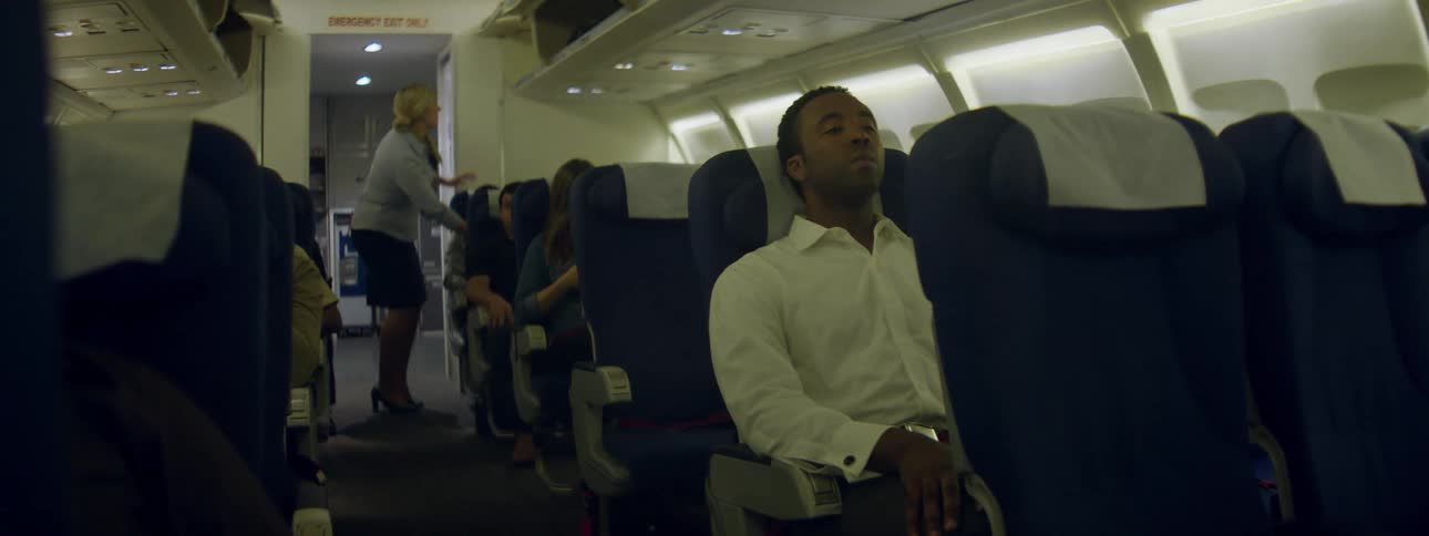 Stewardess brings a pillow to a passenger then closes some overhead bins