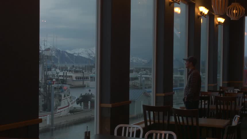 A man looks out a window in an empty restaurant