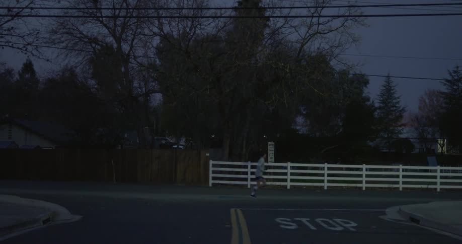 A person jogs along a suburban roadway at night