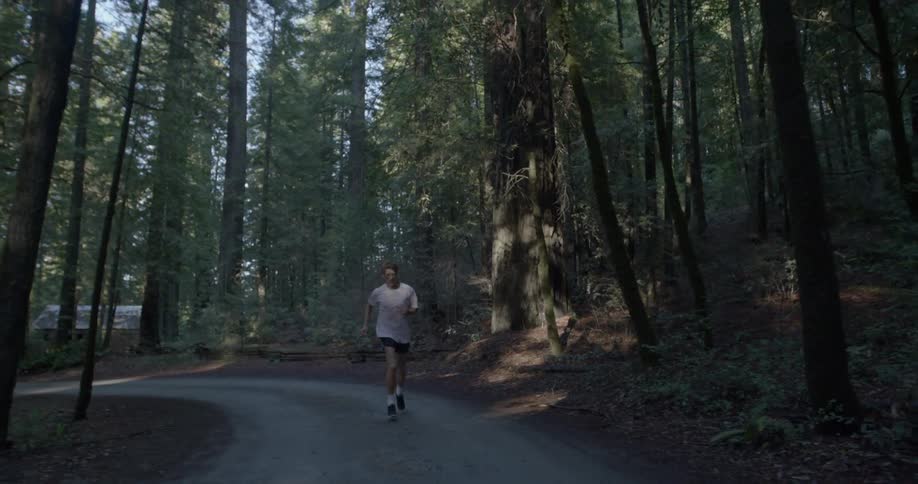 A man jogs down a path in a forest