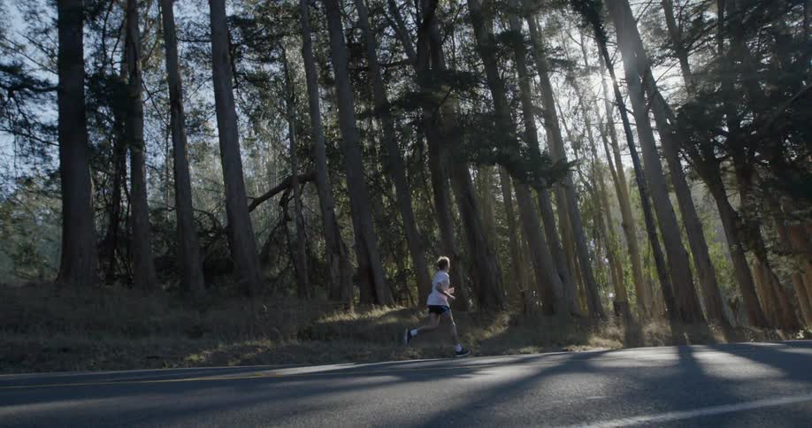 A man jogs down a road in the forest