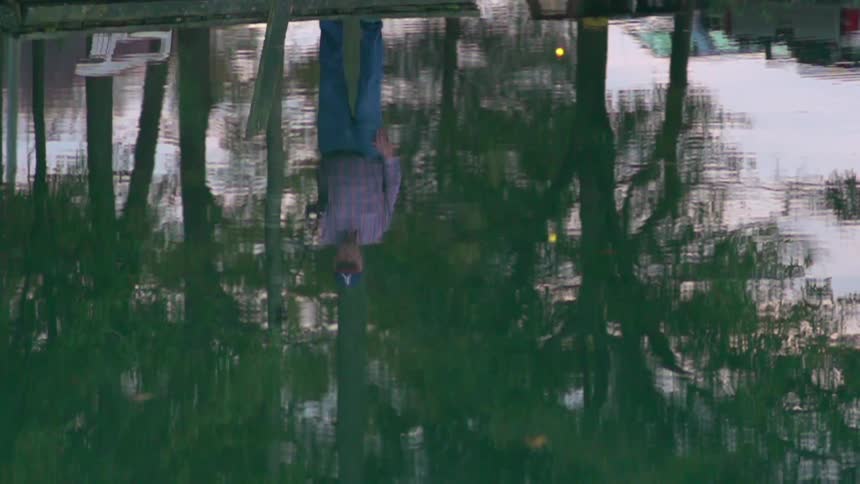 A person stands on a pier while fishing