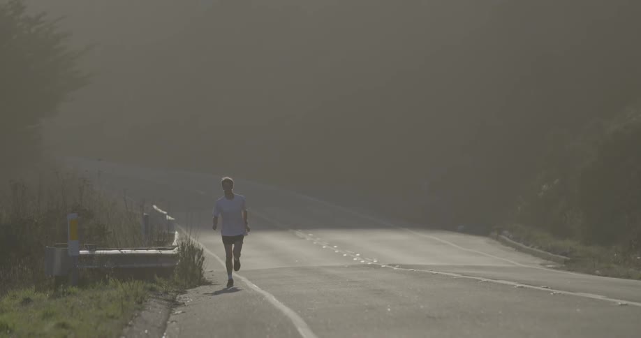 Slow motion shot of a man running on the side of a road