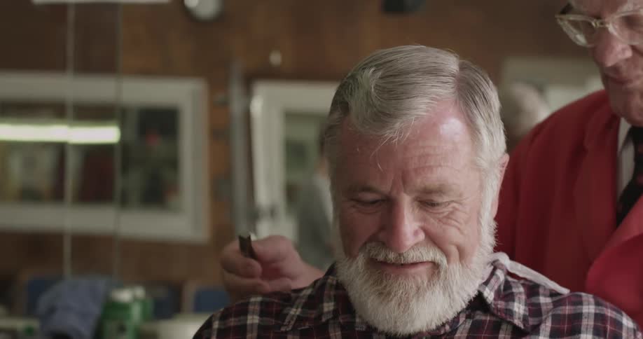 A man laughs and smiles at the barber