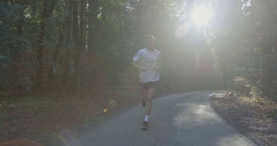 Man running down a small road on a sunny day
