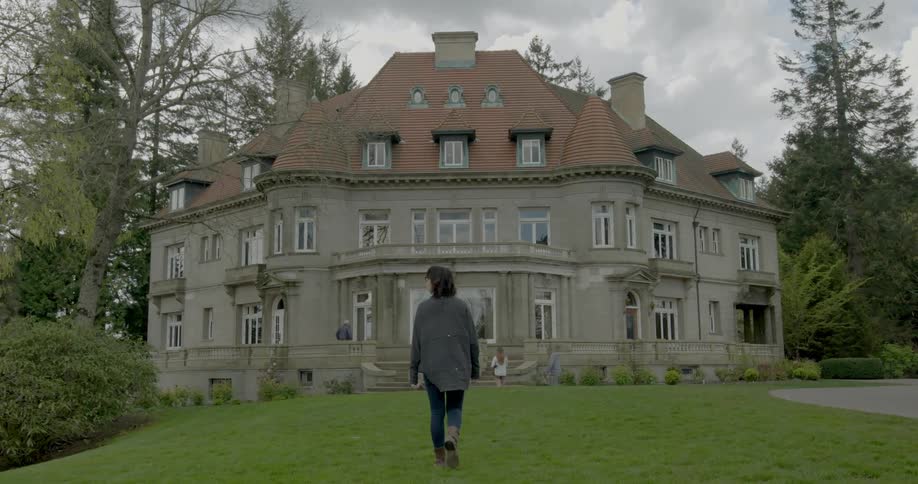 Woman walks across the grass toward the Pittock Museum