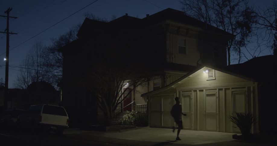A man jogs by a house at night