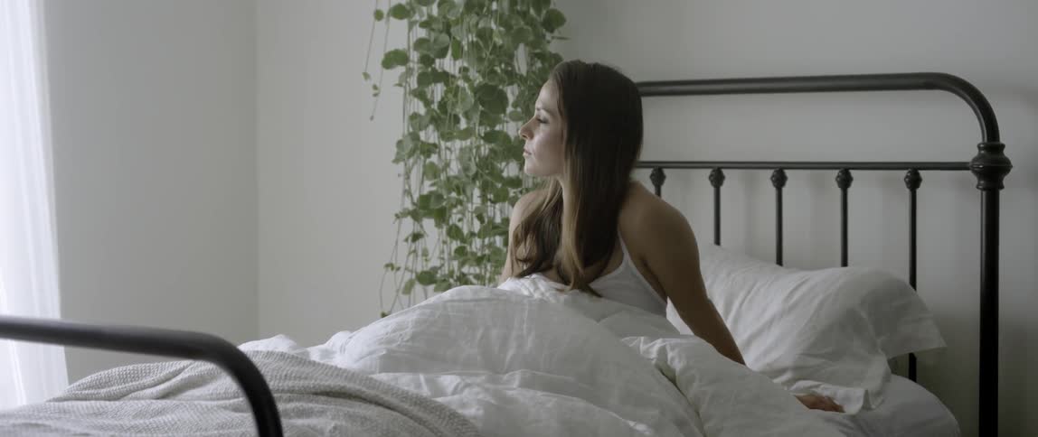 A woman is sitting in a bed and looking around her